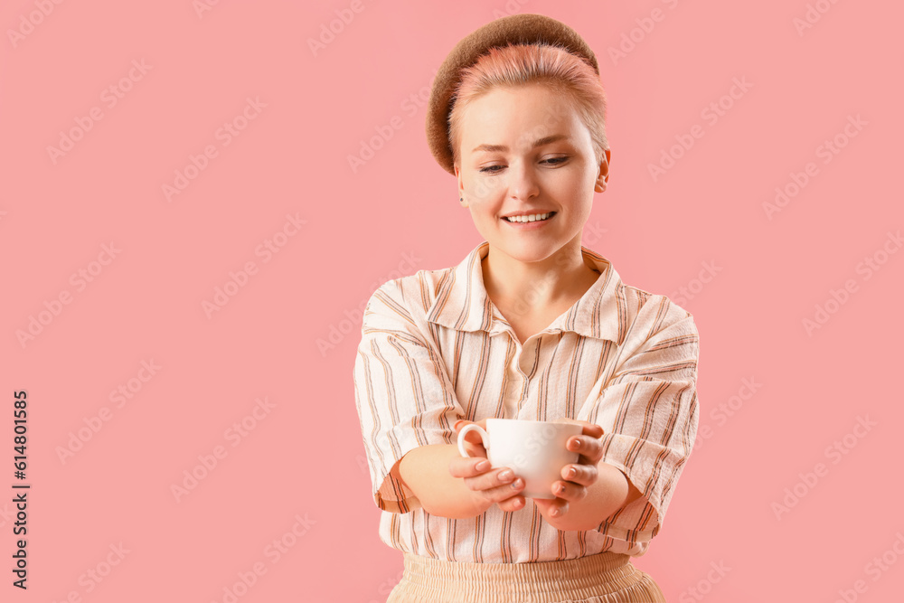 Young woman with cup of coffee on pink background