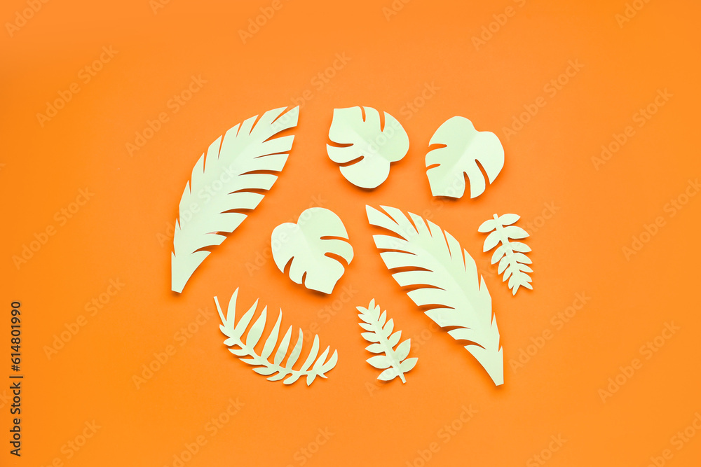 Light paper tropical leaves on orange background