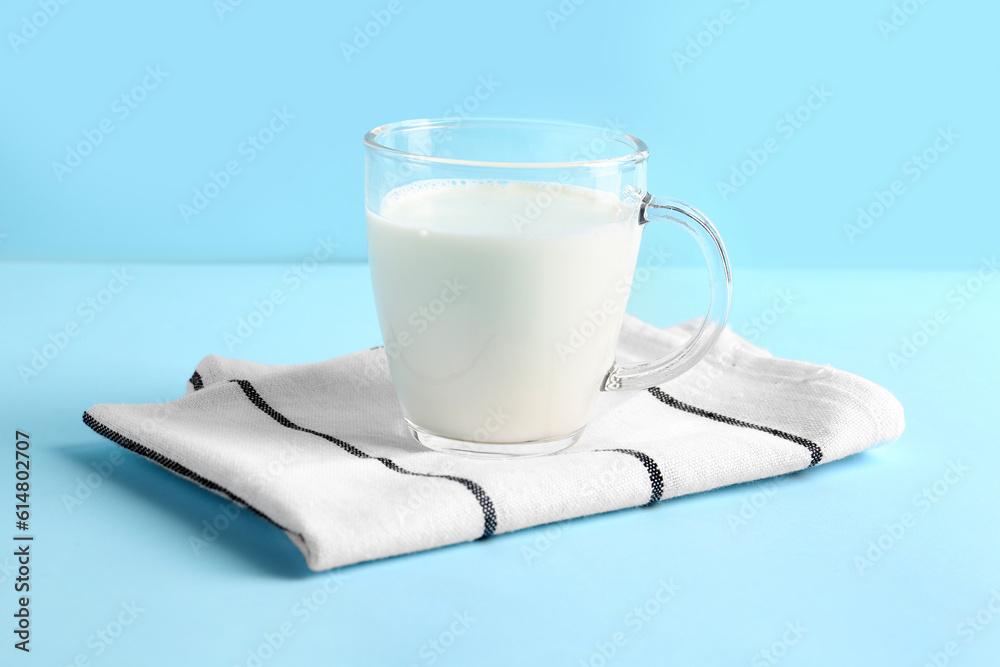 Glass cup with fresh milk on blue background