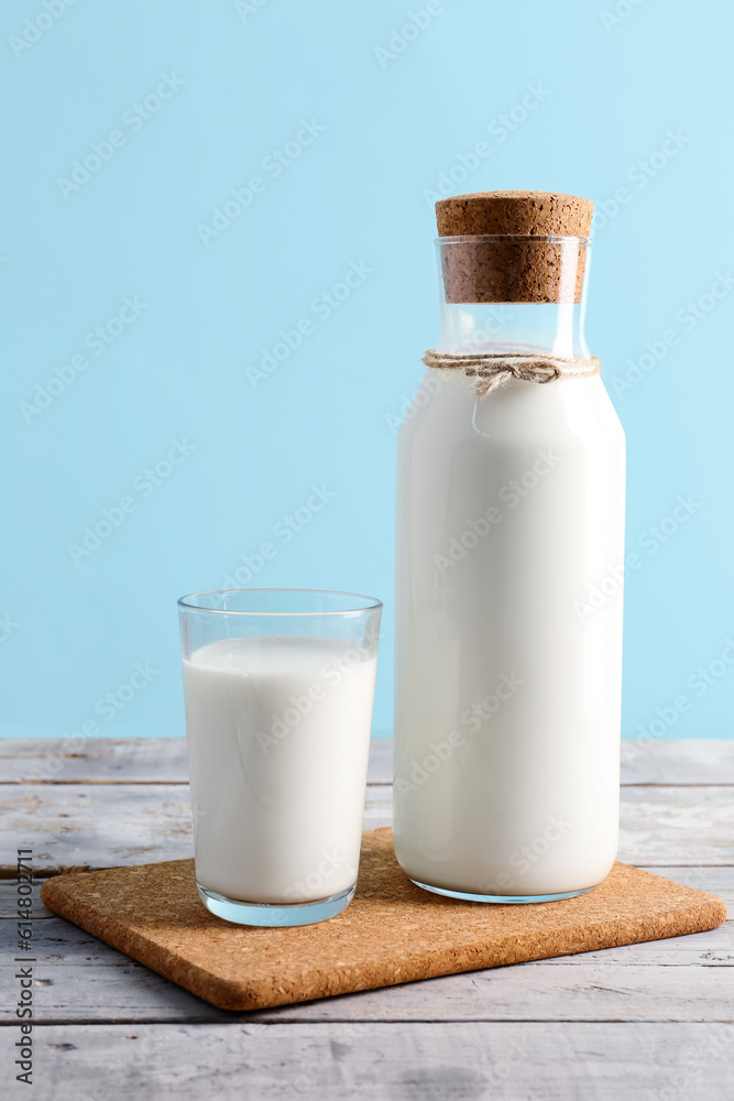 Bottle and glass with fresh milk on grey wooden table