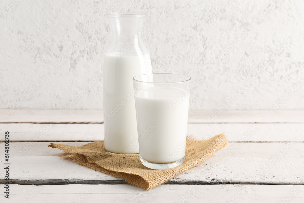 Bottle and glass with fresh milk on light wooden table