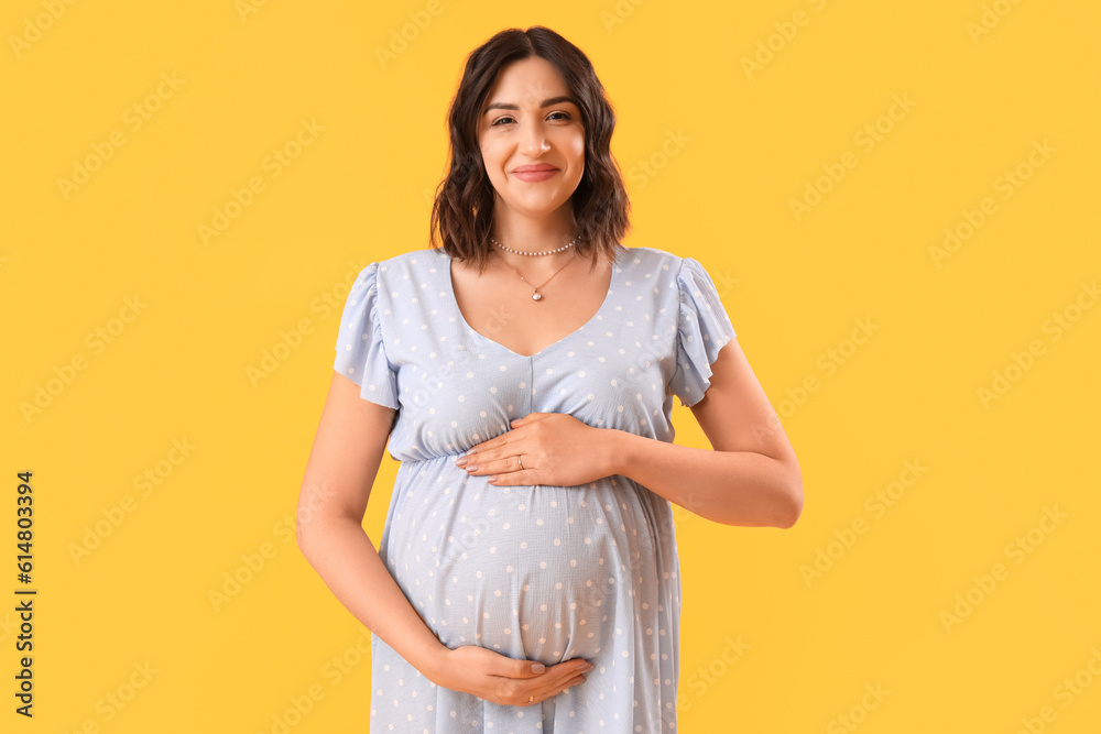 Young pregnant woman on yellow background