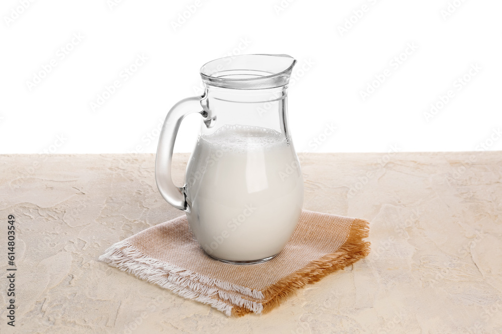 Jug of milk on table against white background