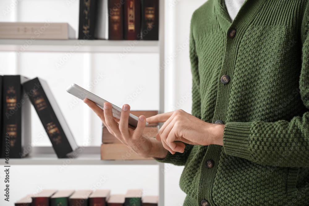 Male student studying with tablet computer in library, closeup