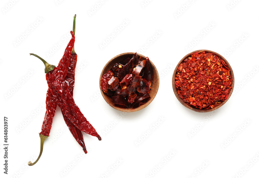 Dry chili with bowls of ground and sliced pepper on white background