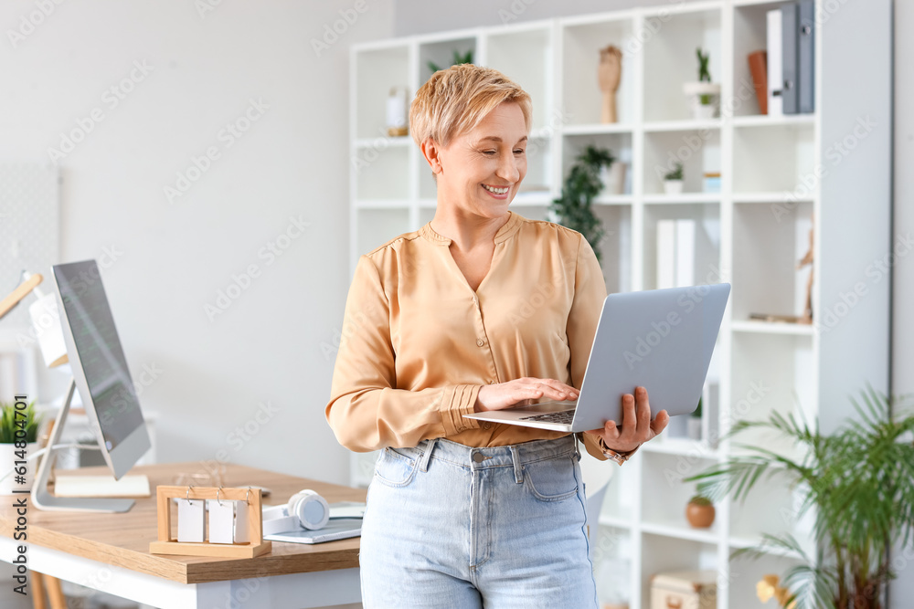 Mature female programmer with laptop in office