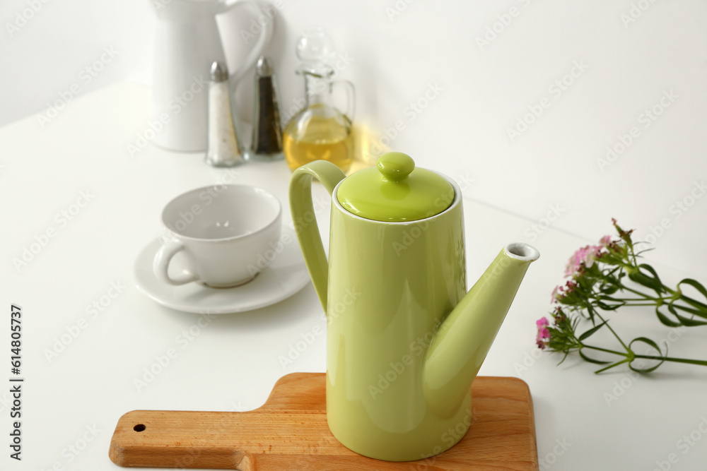 Composition with teapot, cup and different items on white table