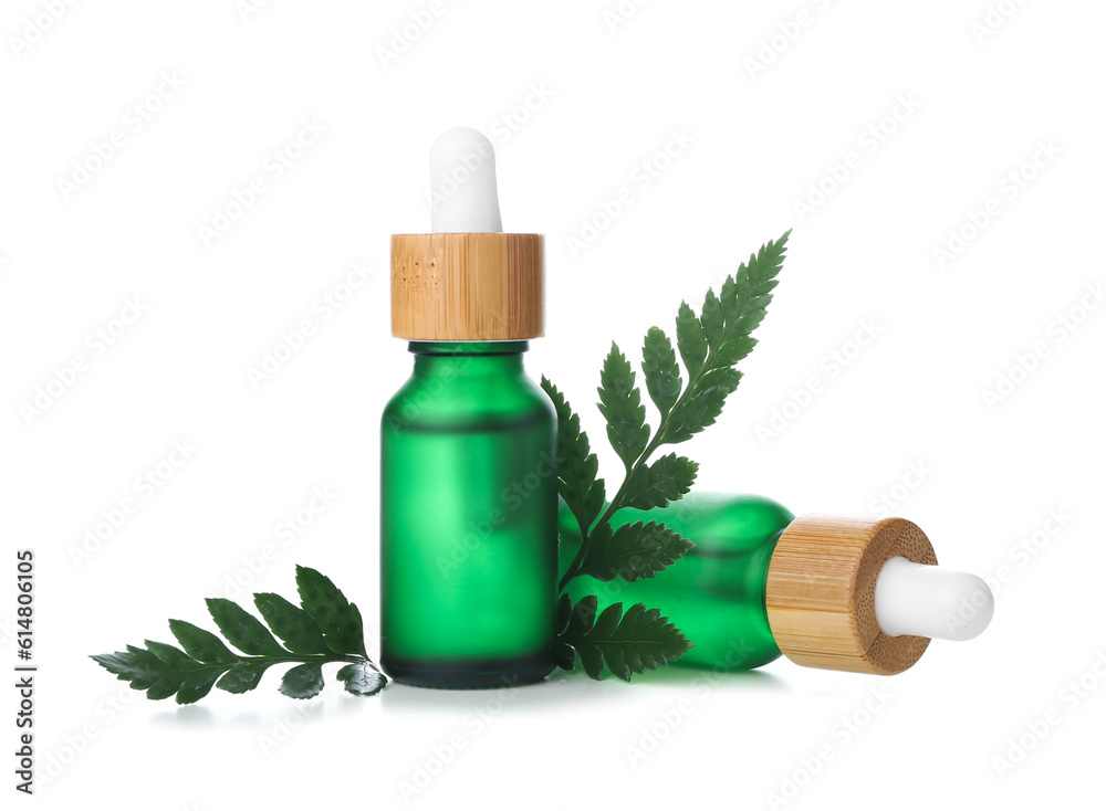 Bottles of cosmetic oil with plant twig on white background