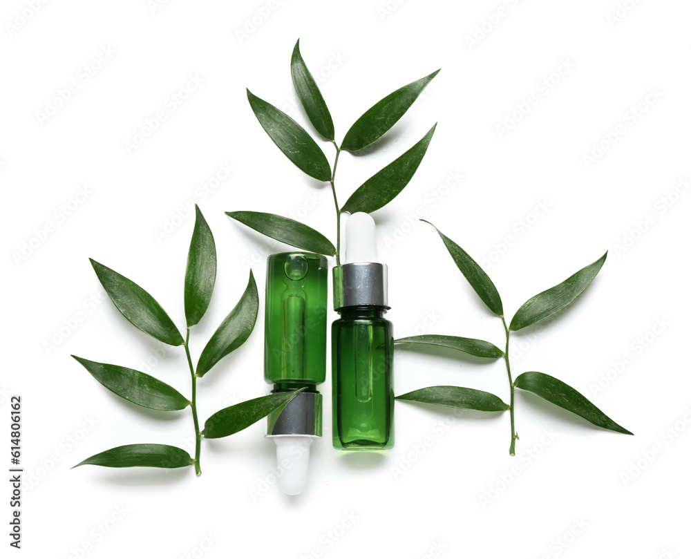 Bottles of cosmetic oil with plant twig on white background