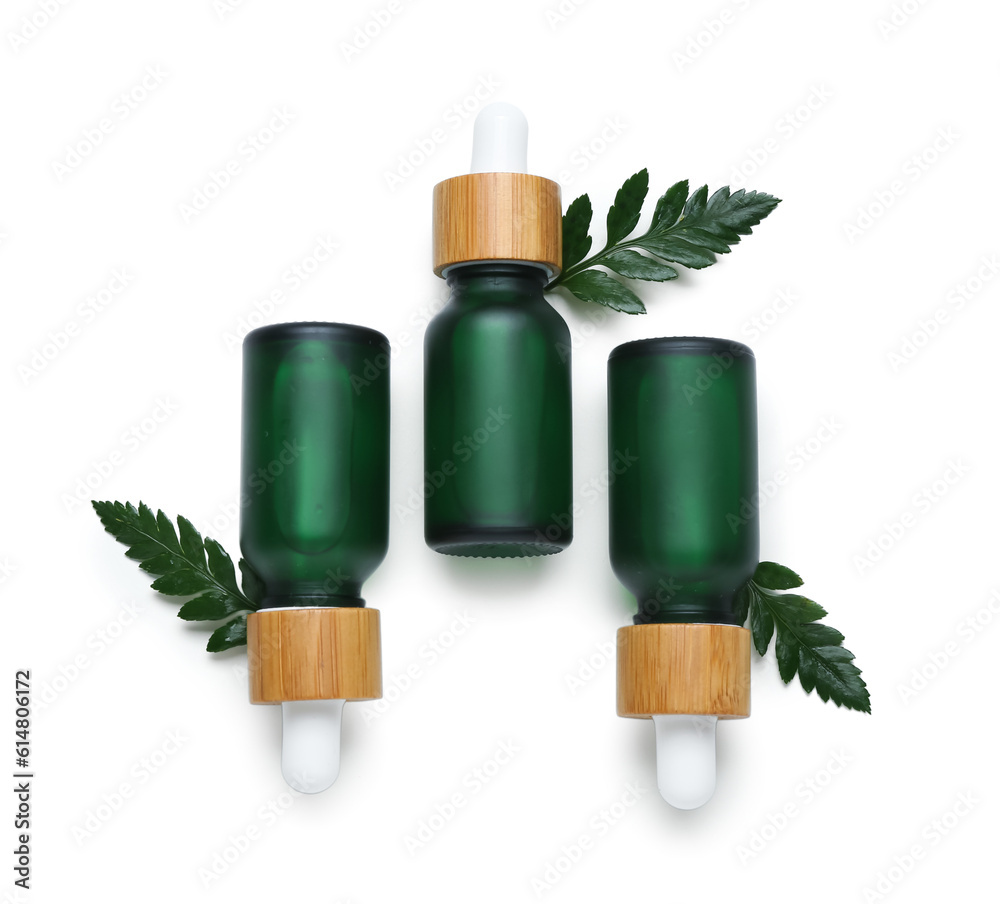 Bottles of cosmetic oil with plant twig on white background