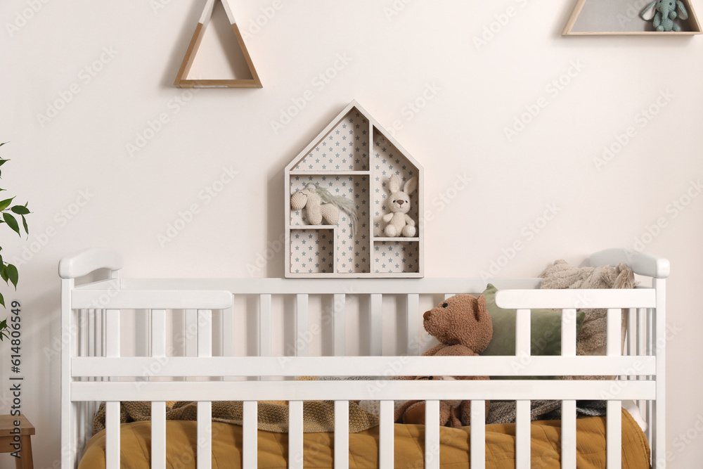 Baby crib with toy bear in light bedroom