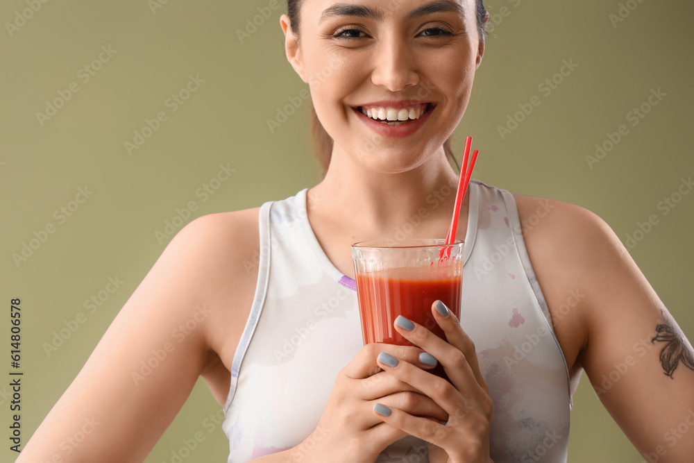 Sporty young woman with glass of vegetable juice on green background, closeup