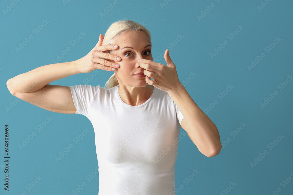 Mature woman doing face building exercise on blue background