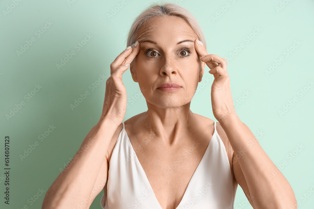 Mature woman doing face building exercise on green background, closeup