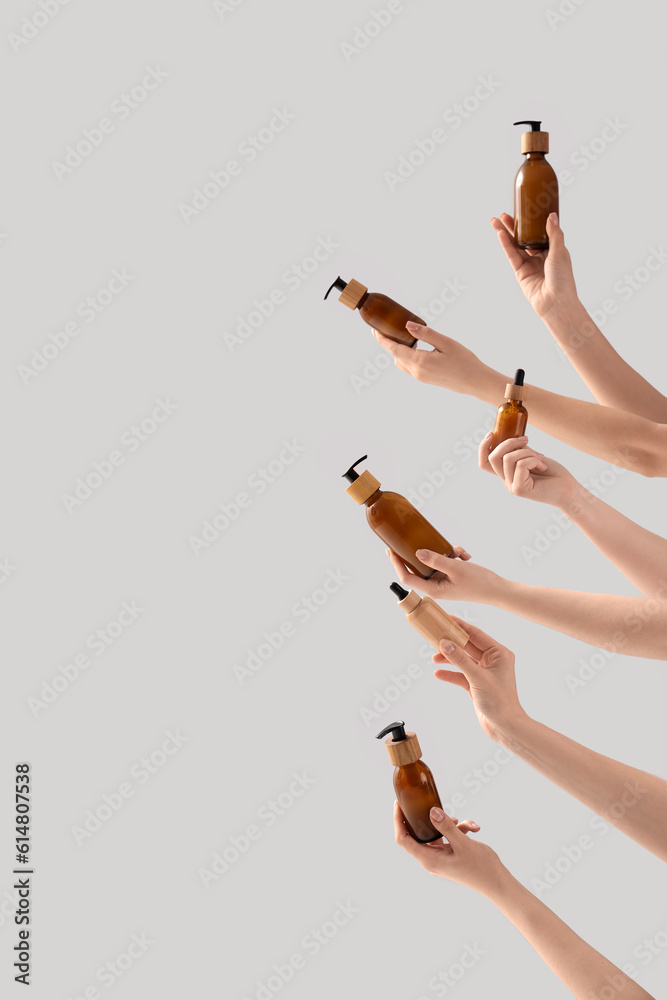 Hands holding different cosmetic products on light background