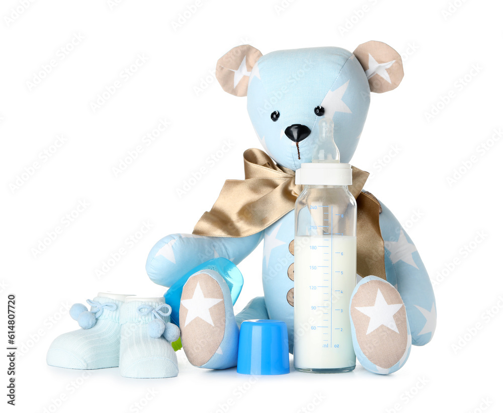 Teddy bear with bottle of milk for baby and booties on white background