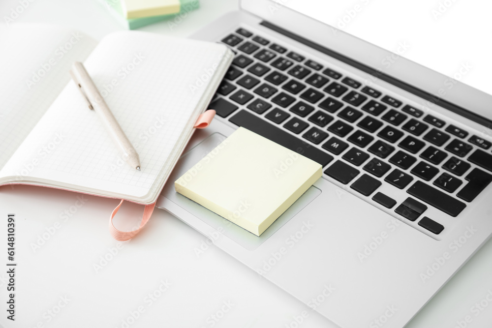 Laptop with sticky notes on white table