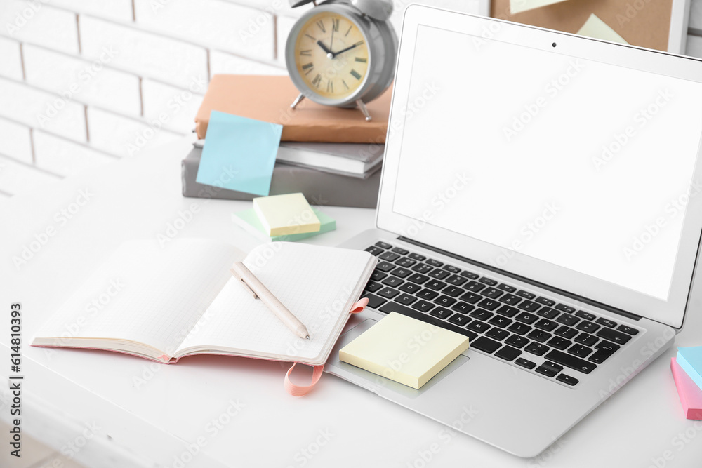 Laptop with sticky notes on white table