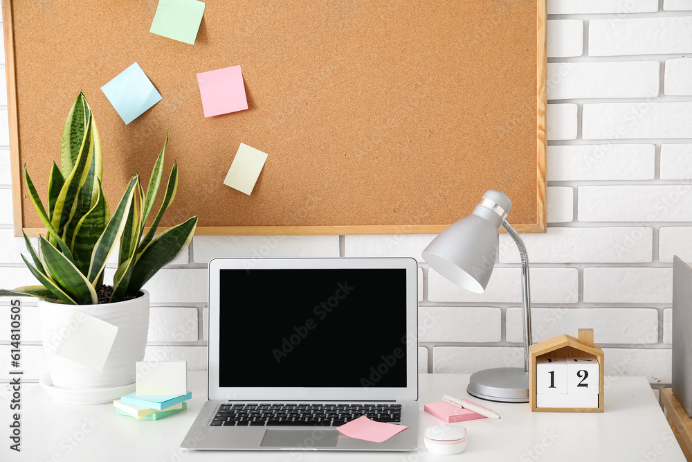 Board with sticky notes and laptop on table in room