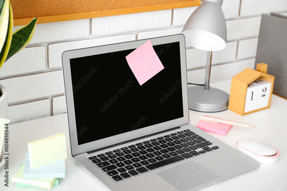 Laptop with sticky notes on white table