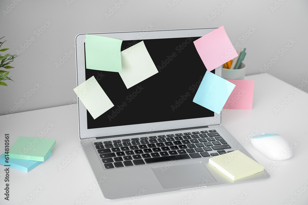 Laptop with sticky notes on white table