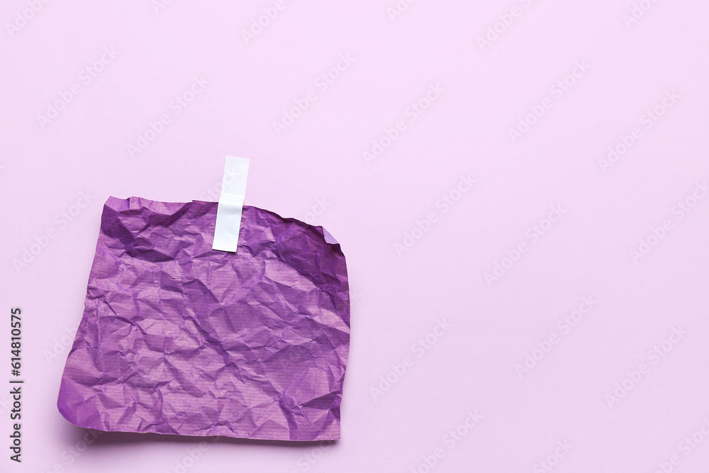 Crumpled paper sheet with adhesive tape on lilac background