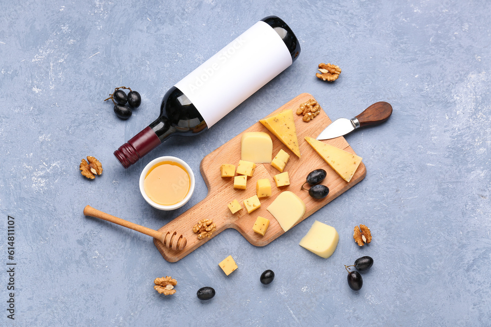 Pieces of tasty cheese, bottle with wine and honey on grey background