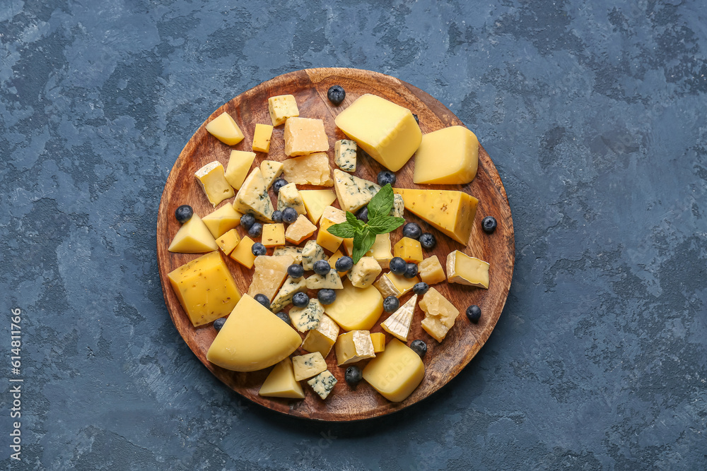 Plate with pieces of tasty cheese on blue background