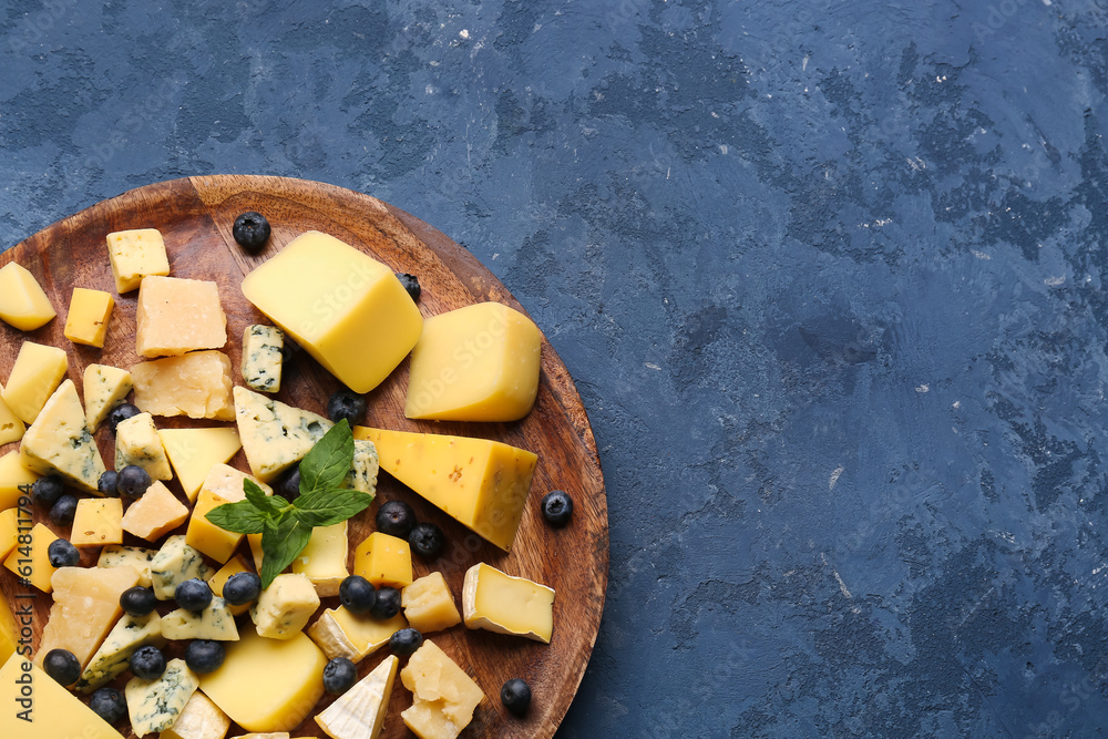 Plate with pieces of tasty cheese on blue background, closeup