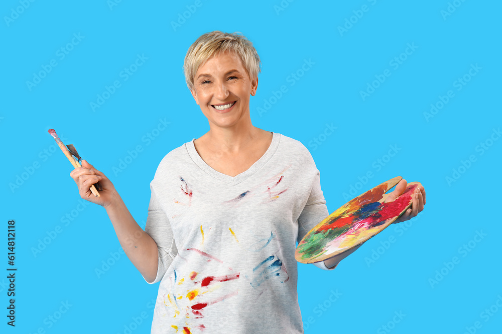 Mature female artist with tools on blue background