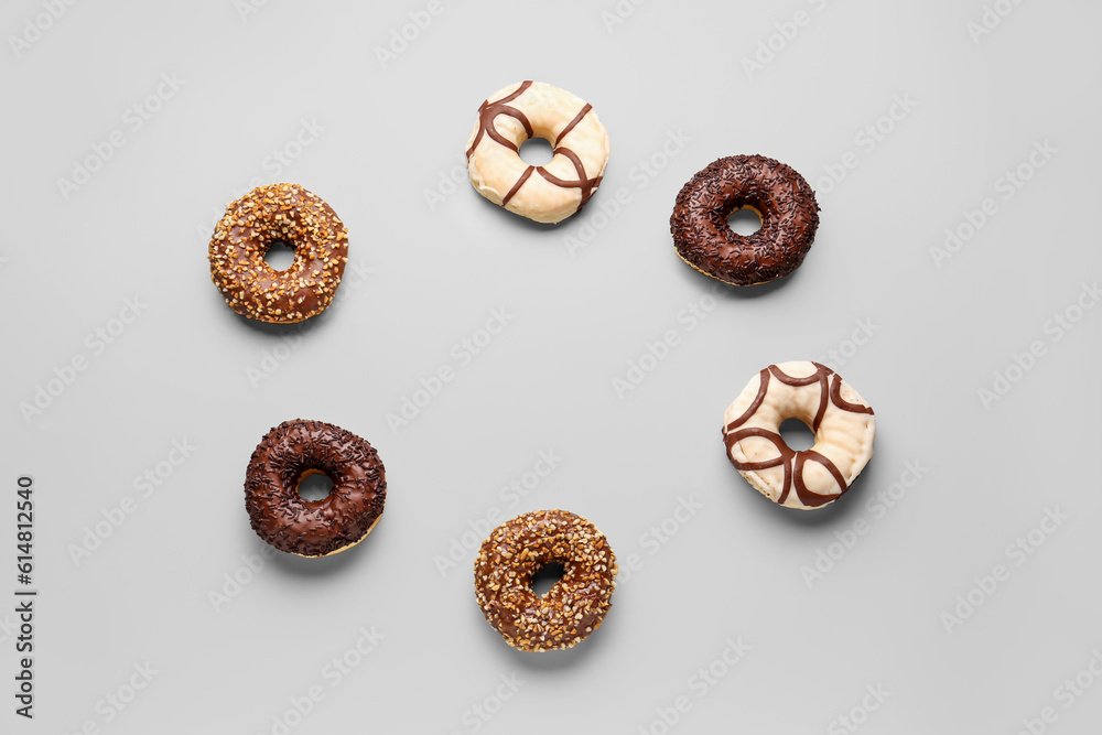 Frame made of sweet chocolate donuts on grey background