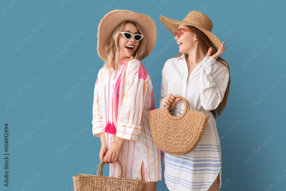 Young sisters in summer hats and sunglasses on blue background