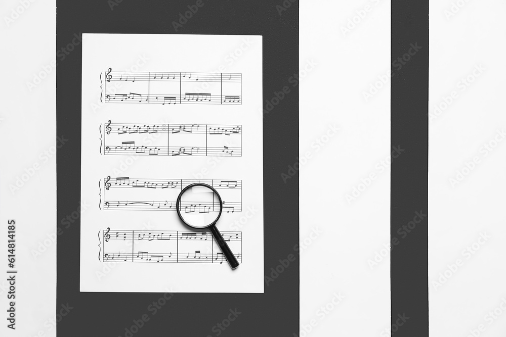 Magnifier with music sheet on black and white background