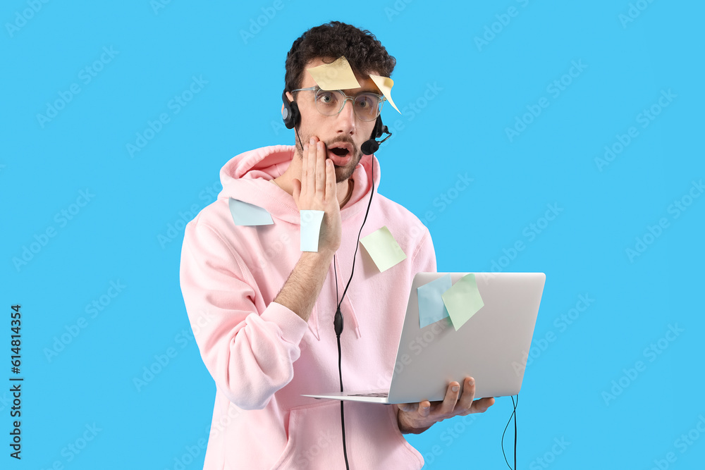 Male technical support agent with laptop and sticky notes on blue background