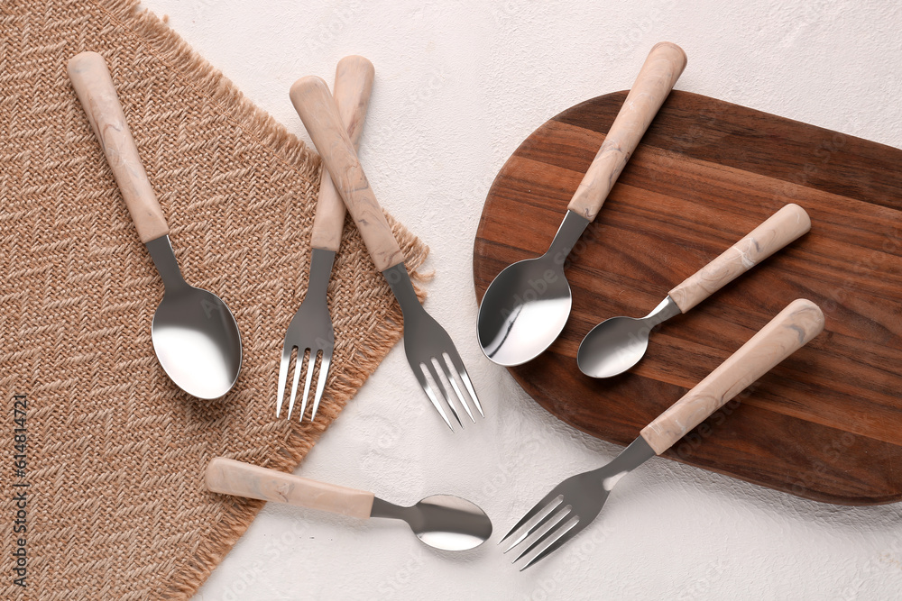 Board with stainless steel forks and spoons on white background