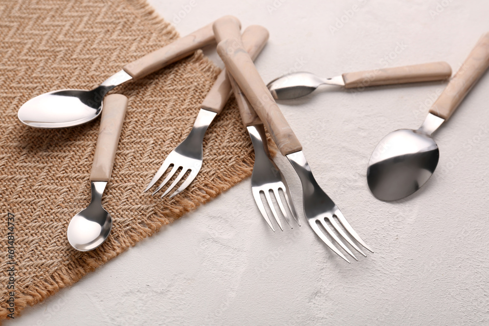 Board with stainless steel forks and spoons on white background