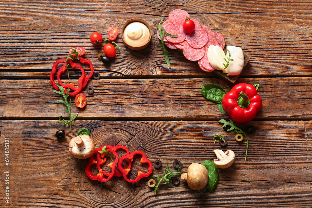 Frame made of fresh ingredients for preparing pizza on wooden background