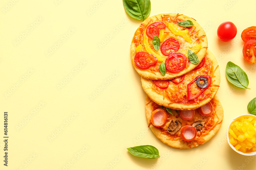 Different tasty mini pizzas on yellow background