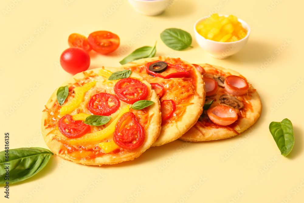 Different tasty mini pizzas on yellow background