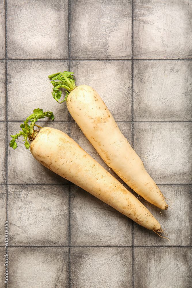 Fresh daikon radishes on grey tile background