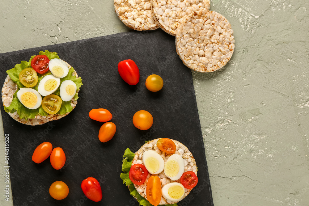 Rice crackers with quail eggs, tomatoes and lettuce on color background