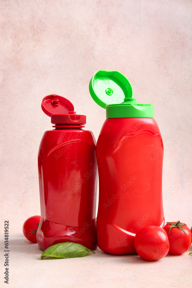 Bottles of ketchup and tomatoes on white background