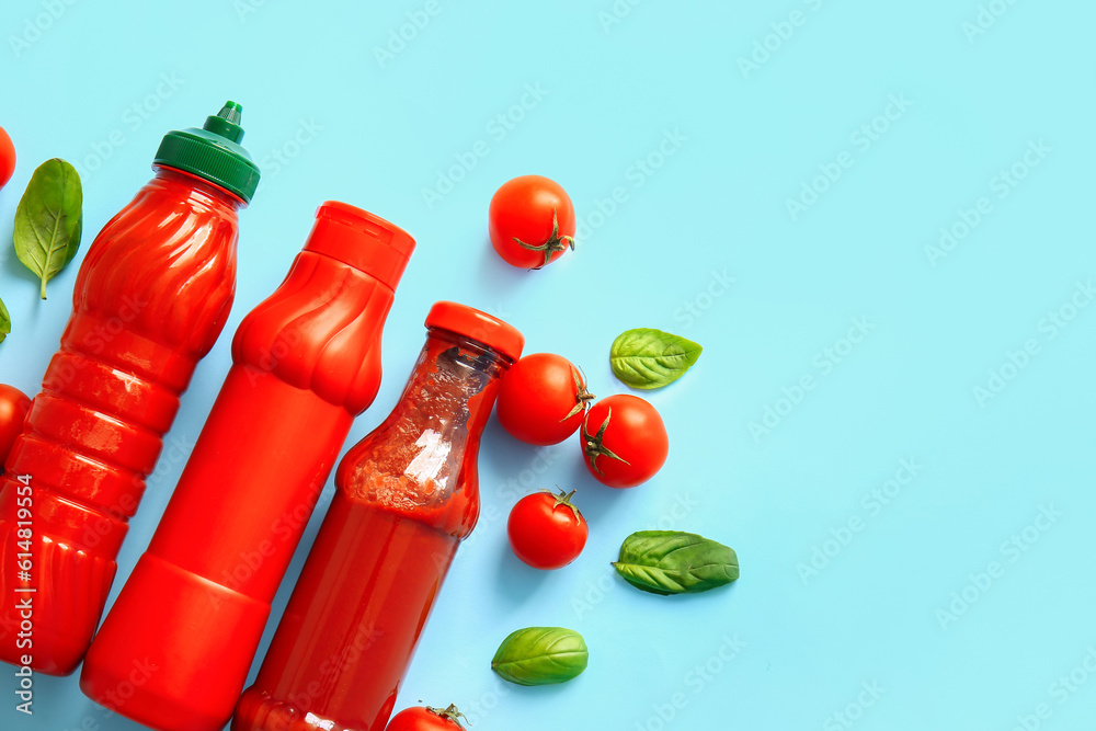 Bottles of ketchup and tomatoes on blue background