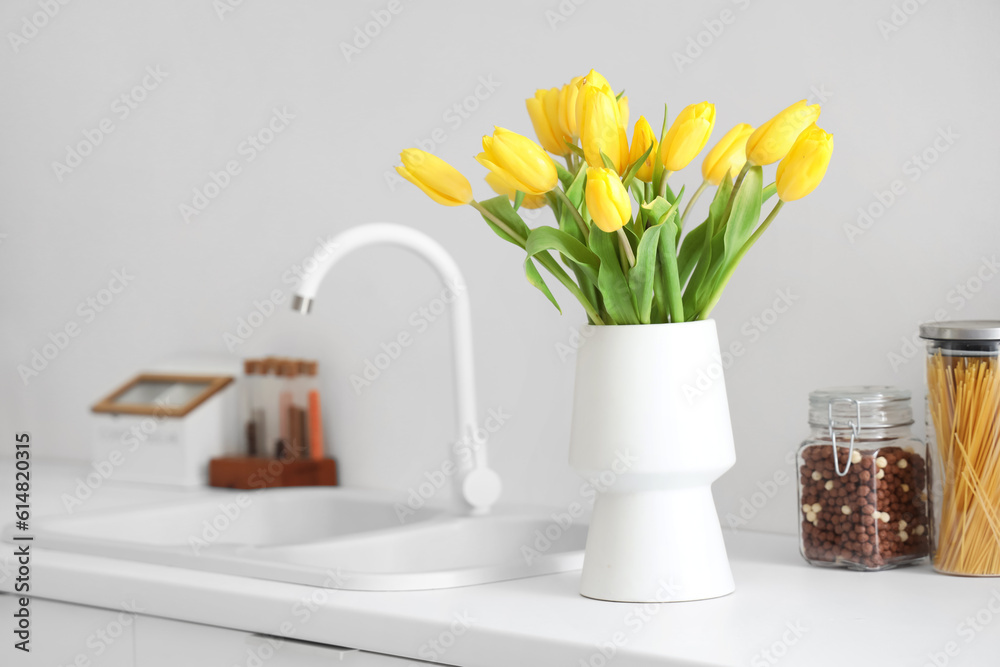 Vase with yellow tulip flowers on countertop near kitchen sink