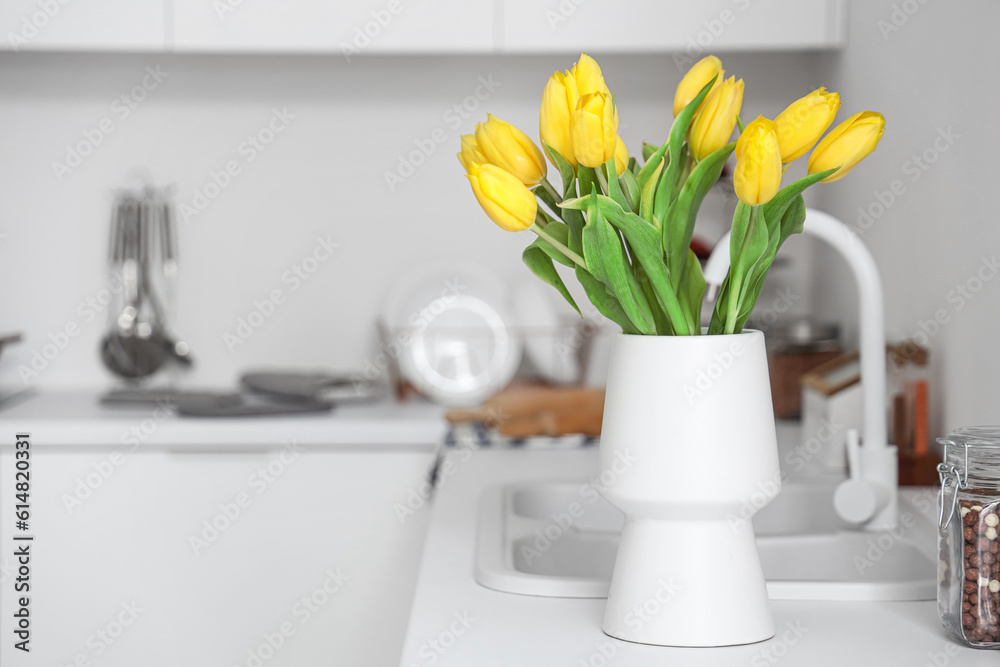 Vase with yellow tulip flowers on countertop near kitchen sink