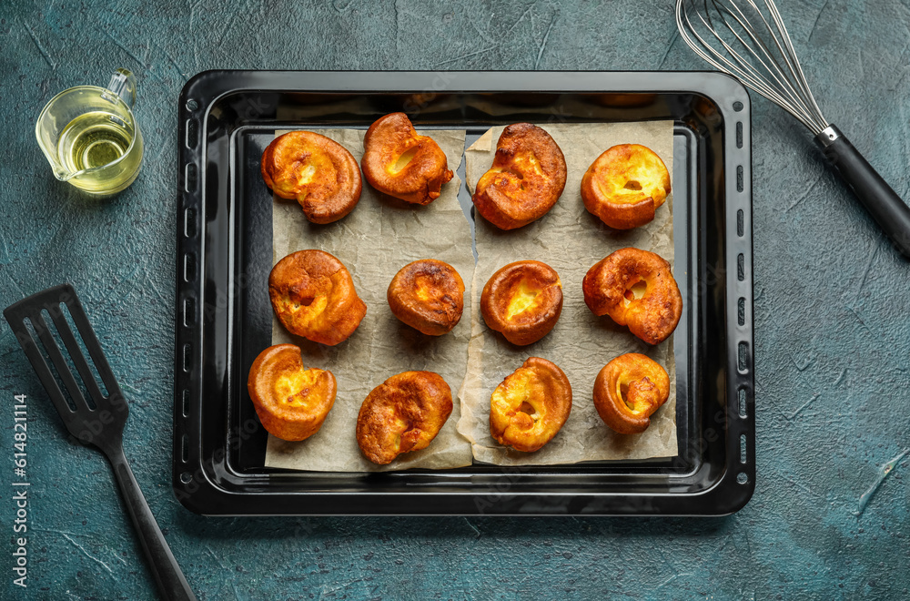 Baking tray with tasty Yorkshire pudding on blue background