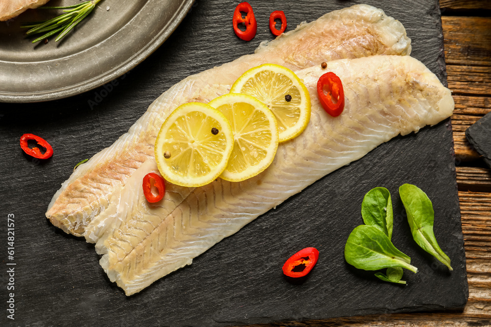 Slate board of raw codfish fillet with lemon on table