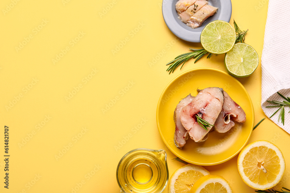 Pieces of raw codfish with lime and lemon on yellow background