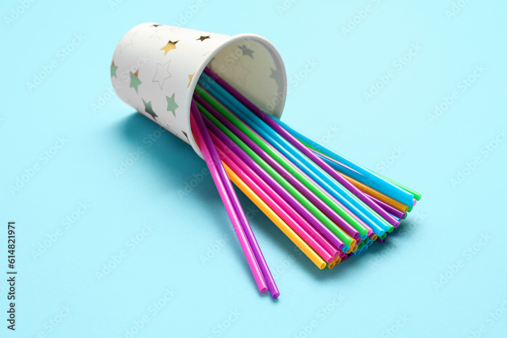 Paper cup with different plastic straws on blue background