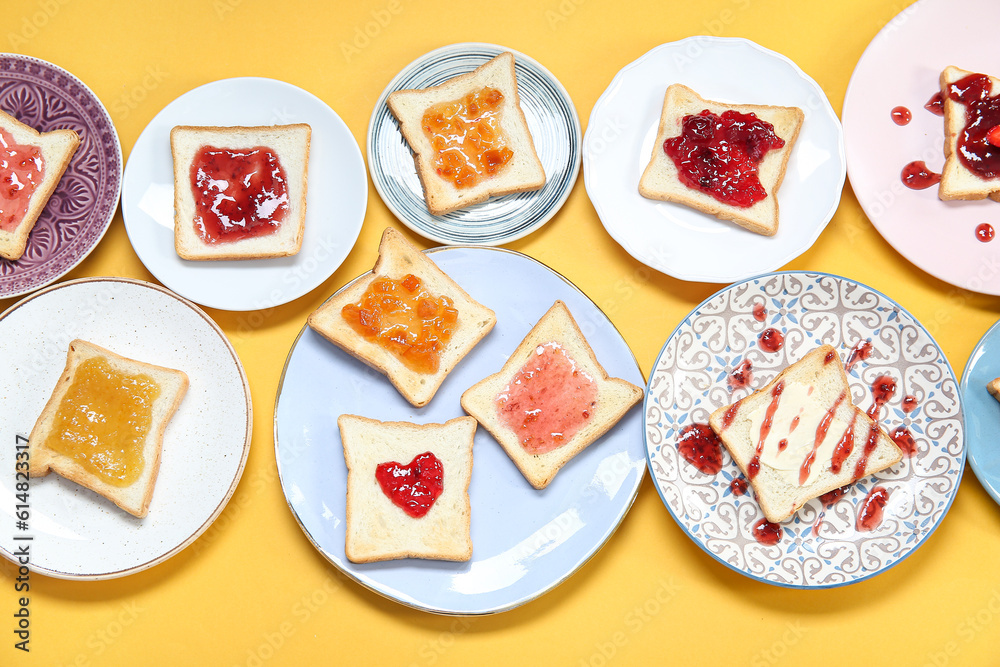 Many plates of delicious toasts with jam on color background, closeup